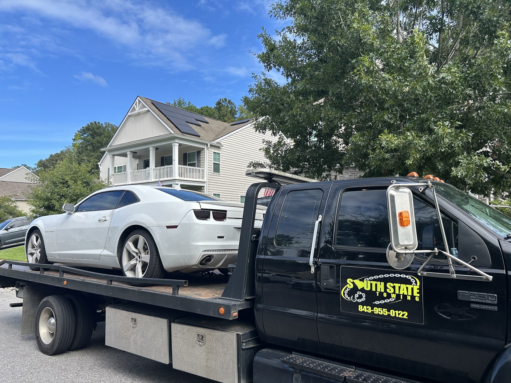 South State Towing flatbed carrying a white Camaro down a Summerville street