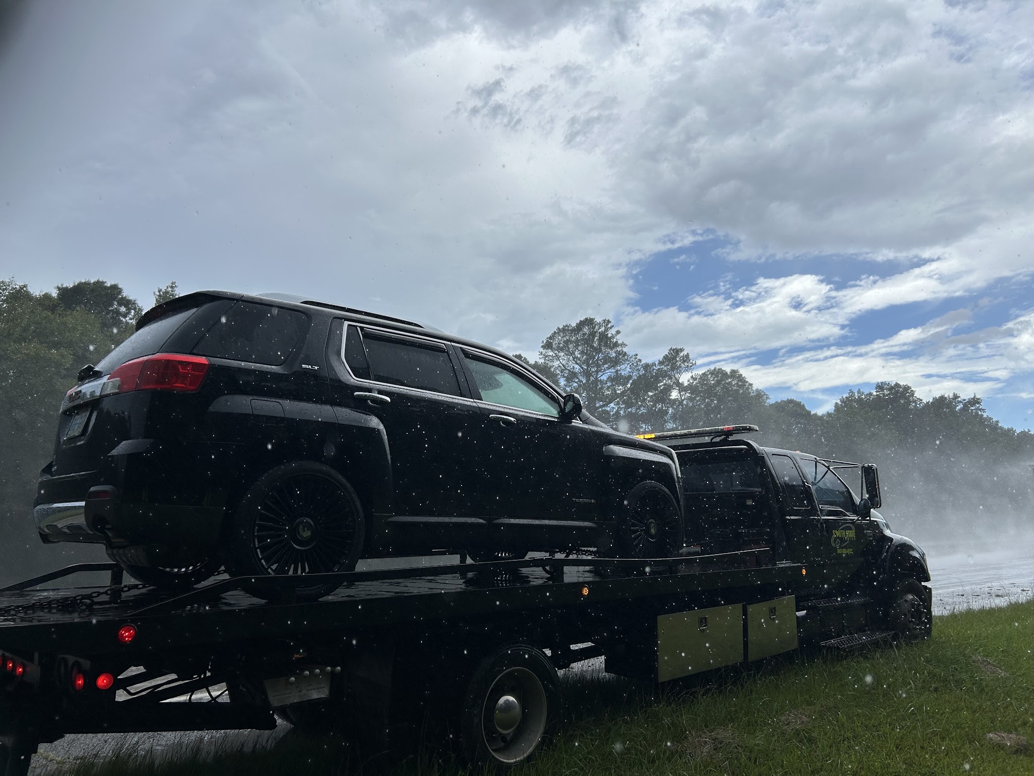 Our truck hauling a black SUV in the rain