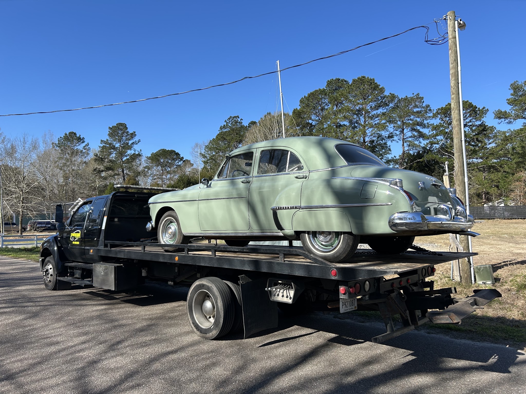 A vintage green sedan loaded on our truck